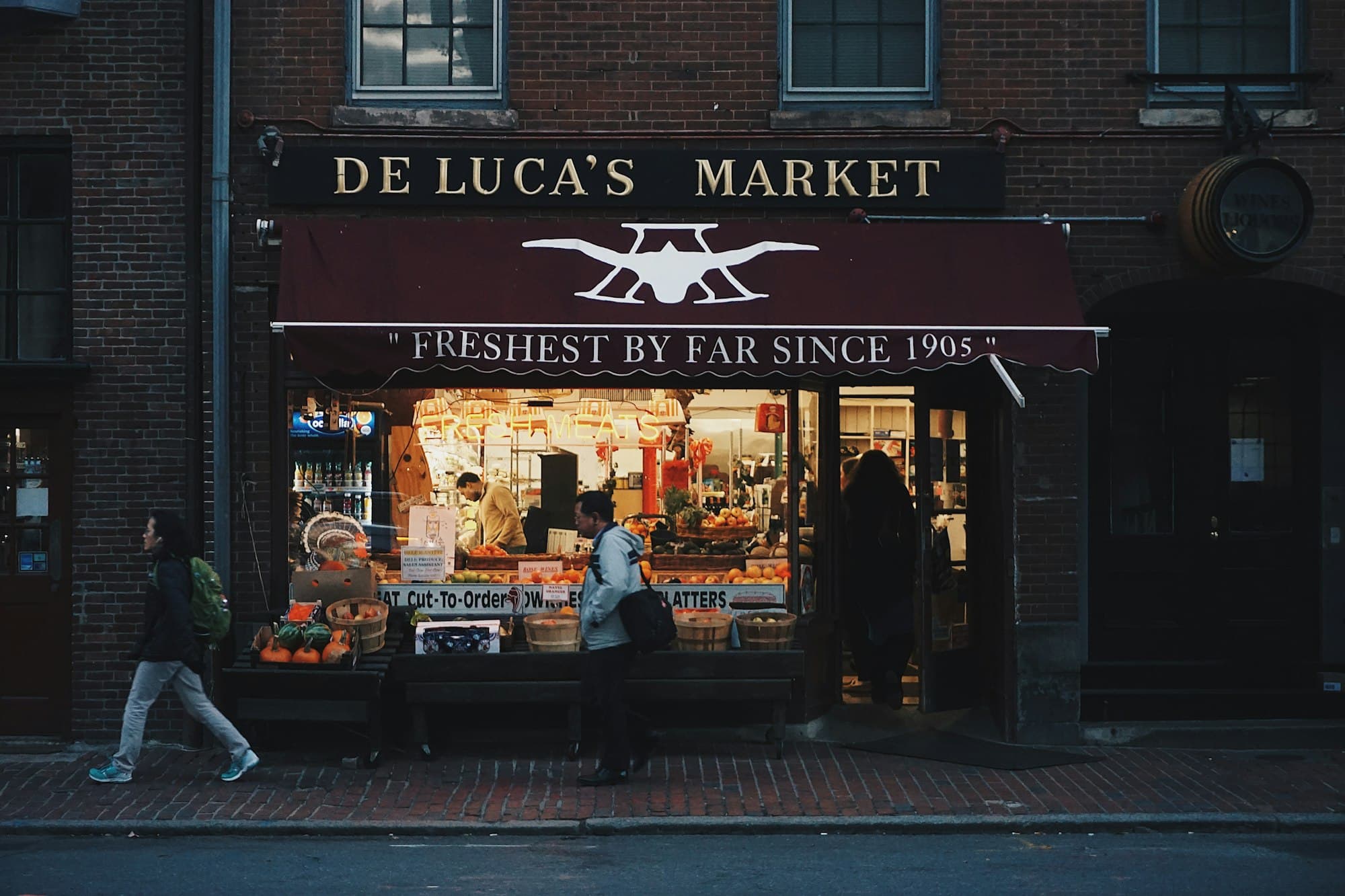 People walking past a neighborhood corner market in Boston